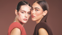 Due donne dai capelli lisci posano una accanto all'altra; una ha il trucco appena abbozzato sul viso, mentre l'altra ha un look completo.
