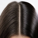 A close-up of the top of a person’s head shows a clear center part in shiny dark hair, revealing scalp along the parting—ideal for applying SIERO 6 - Trattamento rinforzante per crescita capelli e per cuoio capelluto.
