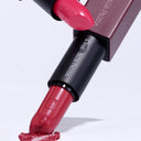 Two Tell Me Lies - Rossetto Cremoso lipsticks by Diego Dalla Palma—one angled downward, touching a smear of red lipstick, the other positioned above it—both with visible branding against a light background, beautifully highlighting the rich texture and irresistibly smooth color for full, luscious lips.