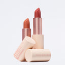 Tre tubetti di Protect My Lips - Balsamo Labbra Protettivo Spf50+ nelle tonalità nude e rosa si ergono verticalmente su uno sfondo bianco. La confezione beige chiaro con accenti oro rosa unisce l'eleganza alla protezione solare delle labbra.