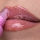 Close-up of glossy lips as a person applies Peptize My Lips - Burro Labbra con Peptidi Volumizzante Idratante with a pink tube. Lips look smooth, hydrated, and slightly plumped thanks to peptides in the formula.