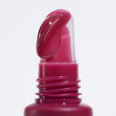 A close-up of a pink lip gloss applicator with a dollop of glossy, deep pink Peptize My Lips - Burro Labbra con Peptidi Volumizzante Idratante on the curved tip, set against a plain white background.