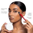 A person uses a red brush to apply Cipria in Polvere Levigante from a compact for a smoothing, natural matte finish, ideal for mature skin.