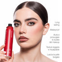 Una donna tiene in mano un flacone rosso di Makeupstudio - Fissatore Trucco Lunga Tenuta, uno spray fissante alla niacinamide, con una scritta che ne sottolinea le proprietà di lunga durata, waterproof e leviganti.