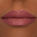 Primo piano di labbra carnose con rossetto malva opaco su una pelle liscia, di carnagione marrone medio. Le labbra appaiono rilassate e sono al centro dell'immagine; si nota la loro texture fine e l'applicazione uniforme del rossetto, esaltata da Plumpfill My Lips - Matita Labbra Effetto Volume, che dona un delicato effetto filler e labbra rimpolpate.