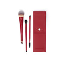 Il set di pennelli imperdibile, composto da tre pennelli da trucco con manico rosso e un pennellino a spirale, è esposto accanto a una custodia rossa con chiusura a scatto.