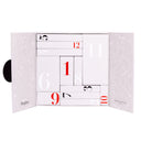 A white rectangular box with open doors reveals the “Beauty Manifesto - Calendario dell’Avvento” by Diego dalla Palma Milano, showcasing black and red numbered compartments of varying sizes. In the background, delicate makeup-inspired illustrations enhance the festive thrill of discovering each beauty product within this special advent calendar.