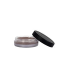 Un piccolo vasetto rotondo con l'etichetta “Setseduce - Gel Fissante Professionale Per Sopracciglia”, con il coperchio nero parzialmente aperto, rivela al suo interno il gel per sopracciglia color taupe. Il prodotto è posizionato su uno sfondo bianco, pronto a creare un effetto naturale.