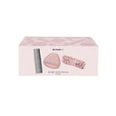 Il kit Be Pure di Diego dalla Palma Milano è contenuto in una confezione rosa pallido e comprende un flacone grigio di mousse struccante, un panno struccante riutilizzabile rosa e un’elegante fascia per capelli rosa con arricciature, tutti raffigurati sulla parte anteriore della confezione.
