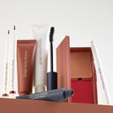 A collection of Diego dalla Palma makeup, featuring the Stain With Me Lip Marker - Penna di Precisione Contorno Labbra, foundation, mascara, and a compact palette with blush and mirror, neatly arranged against a light background.