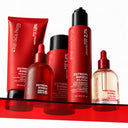 Five red BOND ARCHITECT CPX Balsamo Ultra Riparatore Senza Risciacquo hair care products, including tubes, bottles with pumps, and a dropper bottle, arranged on a red glass shelf.