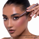 Una modella dalla pelle luminosa tiene vicino alle sopracciglia il FULLFACE SLIM STICK - Matita multiuso in stick viso-occhi-labbra. Indossa la tonalità 88 a lunga durata sulle guance e 83 su occhi e labbra per un look rosato.
