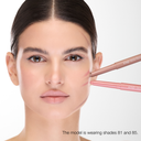 Una donna con eleganti capelli scuri applica due tonalità di FULLFACE SLIM STICK 81 Mauve, 85 Beige sulle guance, lasciando degli schizzi visibili. Testo: "La modella indossa le tonalità 81 e 85. Formula a lunga tenuta". Matita multiuso in stick viso-occhi-labbra.