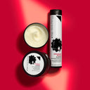 Un barattolo aperto di maschera per capelli accanto a un flacone di shampoo disciplinante modellante orglioriccio, entrambi con grafica in bianco e nero su sfondo rosso.